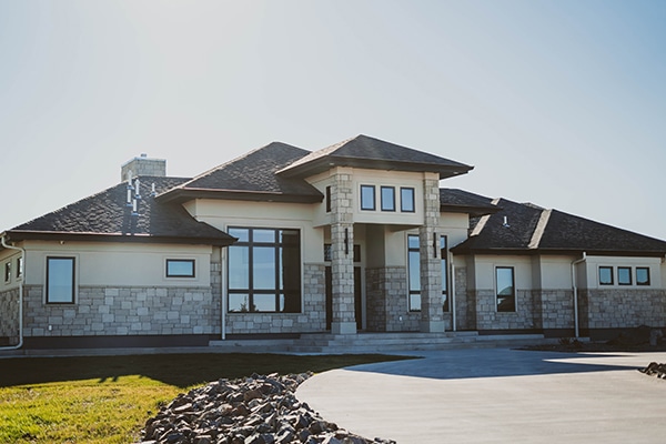 A custom home built in a residential neighborhood with a rock path lining the driveway up to the front door