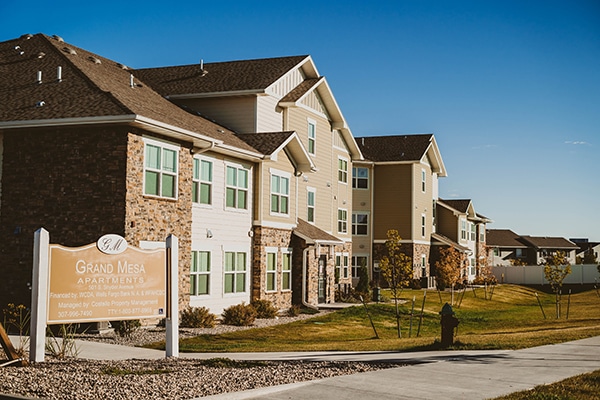 A unit of homes with a sign out front and different levels showing that multiple families can live in the homes